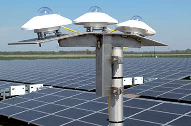 A Kipp & Zonen pyranometer mounted beside an angled, partly snow-covered solar panel.
