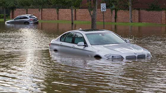 Car submerged in water on flooded street.