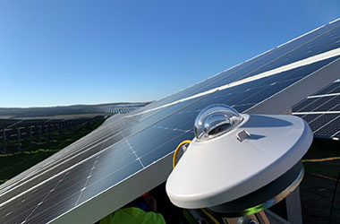 A Kipp & Zonen pyranometer mounted in the foreground of a large solar panel installation.