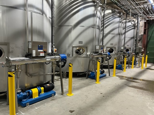Four Aquafine OptiVenn UV systems installed beside four sugar syrup storage tanks in a beverage production facility