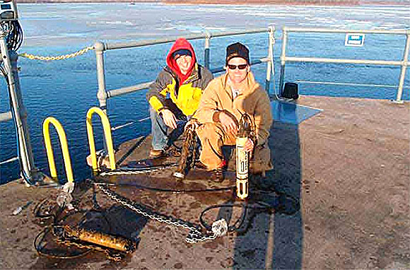 Two scientists monitoring water quality in a half frozen body of water.