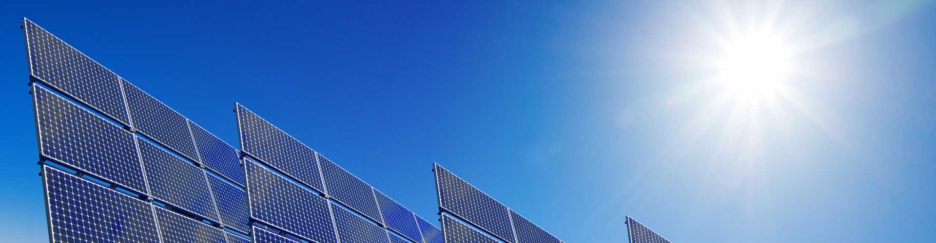 A row of solar panels in full sunlight under blue skies that are supported by OTTHydroMet’s solar instruments.