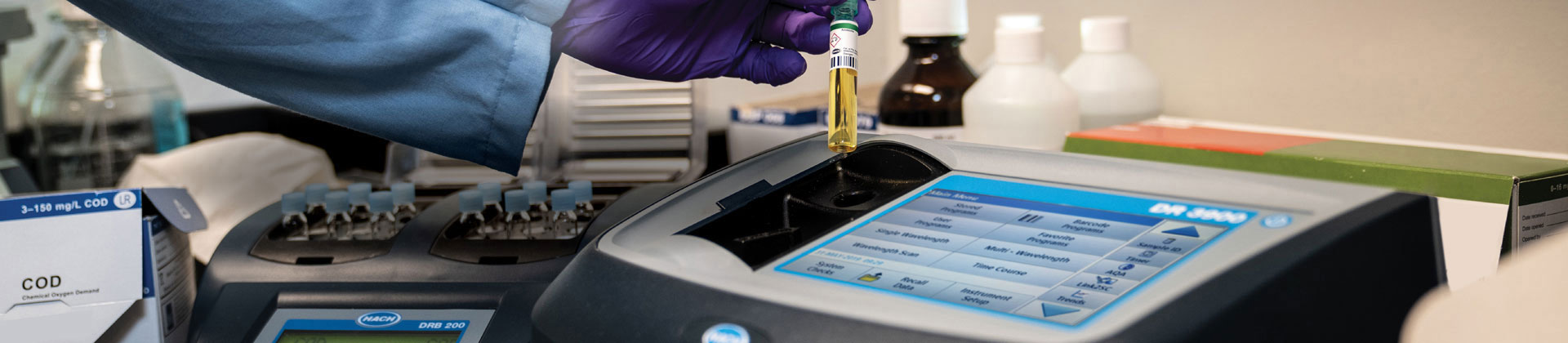 Hand inserting a TNT vial into a Hach Spectrophotometer