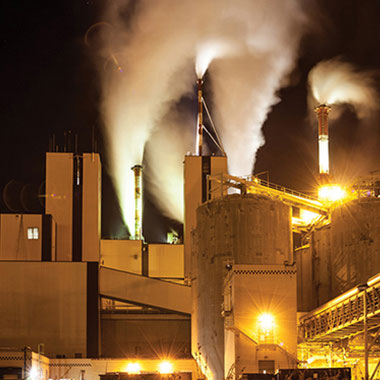 A paper mill lit up at night. Paper mills use sodium sulfite as an oxygen scavenger agent to treat water being fed to steam boilers preventing corrosion.
