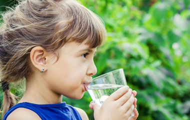 A young girl drinking a glass of water