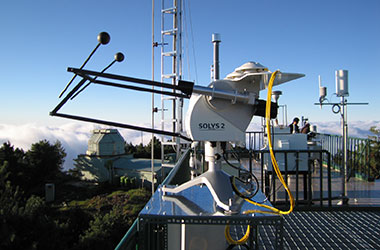 A side shot of a Kipp & Zonen SOLYS2 Sun Tracker on an elevated platform under the sun.
